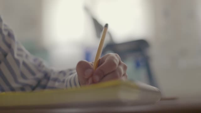 Schüler-männliche-Hand-schreiben-Copybook-In-weißen-Raum-Bildungskonzept
