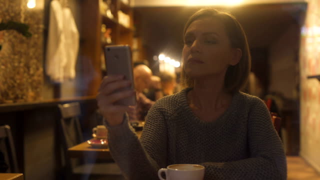 Joven-mujer-chateando-en-smartphone,-sentados-en-la-acogedora-cafetería,-conexión-wi-fi