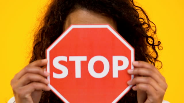 Biracial-Mädchen-hält-Stopp-Schild,-gegen-Mobbing-oder-Rassismus,-Waffengewalt