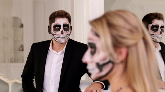 A-girl-with-a-terrible-make-up-for-halloween,-on-background-is-a-man-in-a-suit.