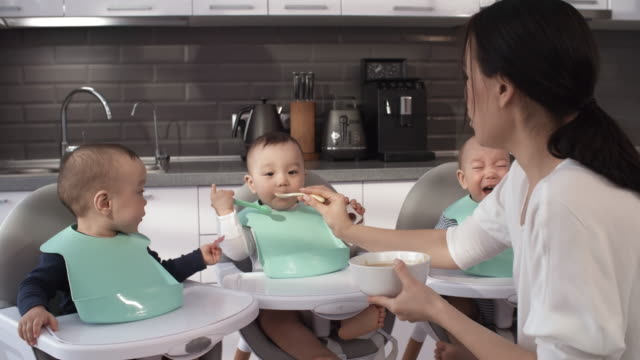 Niñera-filipina-Alimentando-trillizos-de-1-año-de-edad-en-sillas-altas