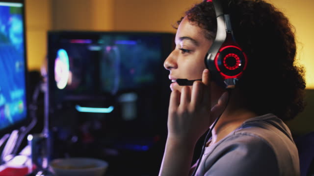 Teenage-Girl-tragen-Headset-Gaming-zu-Hause-mit-Dual-Computer-Bildschirme