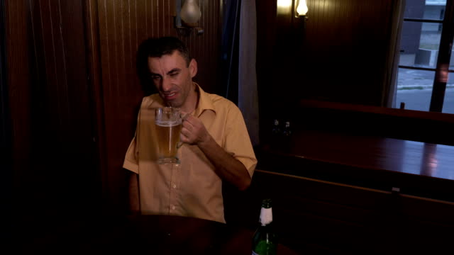 Drunk-guy-sitting-at-a-table-in-a-pub-and-drinking-beer