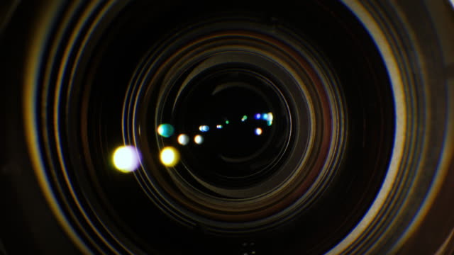 Un-primer-plano-de-la-lente-de-una-cámara-de-vídeo.-La-fuente-de-luz-ilumina-las-lentes,-luego-entra-en-la-oscuridad