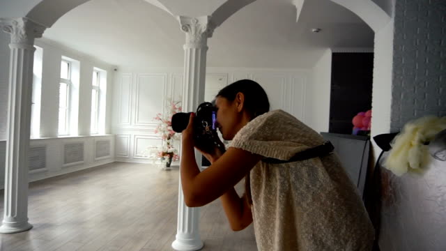 Young-charming-Woman-photographer-taking-photos-with-dslr-camera-indoors-with-grunge-interior-room