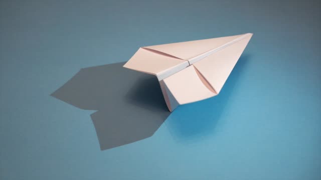 weißes-Papierflugzeug-auf-blauem-Papierhintergrund