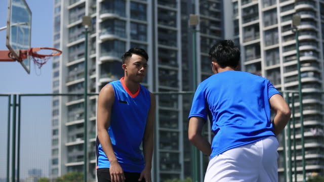 asiatische-junge-Erwachsene-spielen-Basketball-auf-Freiplatz