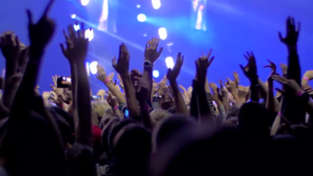 Personas-con-las-manos-para-arriba-en-el-concierto-de-rock,-ve-con-las-luces-del-escenario