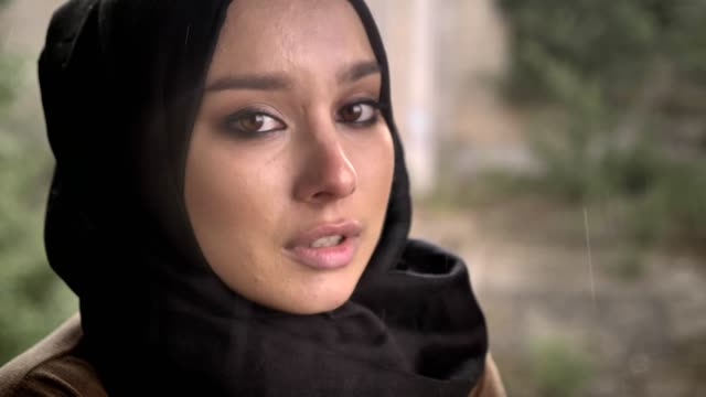 Porträt-der-jungen-Muslima-Hijab-Blick-in-die-Kamera-mit-traurig-deprimiert-Ausdruck-bei-Regen