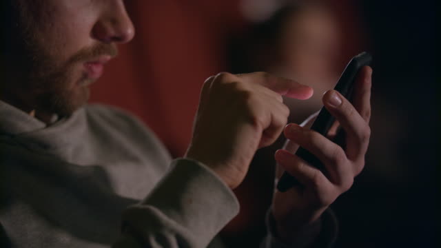 Male-hands-using-mobile-phone-in-cinema.-Man-hands-scrolling-phone-at-theatre