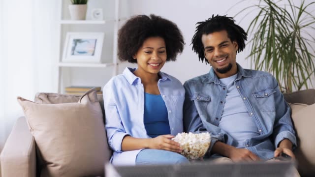 smiling-couple-with-popcorn-watching-tv-at-home