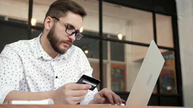 Man-paying-online-by-bank-card-at-laptop