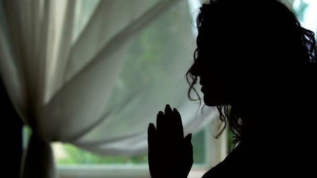 Frau-Silhouette-beten-drinnen,-lesen-ein-mit-Hände-gefaltet,-bat-Gott-beten