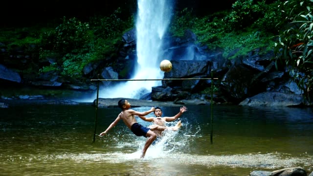 Ländliche-Kinder-schießt-einen-Fußball-am-Wasserfall.-(Zeitlupe)