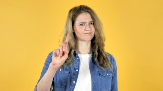 Young-Pretty-Girl-Waving-Finger-to-Refuse-on-Yellow-Background