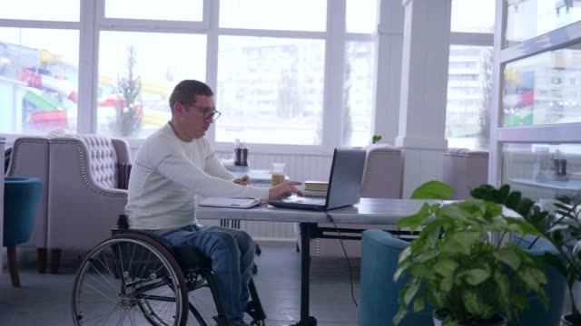 Online-Zahlung,-glücklich-in-Gläser-in-Rollstuhl-mit-Plastikkarte-deaktiviert-macht-Einkäufe-im-Internet-mit-moderner-Computertechnologie-während-während-freiberufliche-Tätigkeit