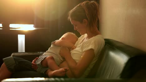 Young-mother,-breastfeeding-on-sunset-on-quiet-evening-her-little-baby-boy-in-sunny-living-room