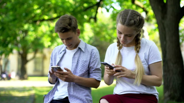 Gadget-addicted-friends-using-phones-in-park,-lack-of-communication,-ignoring