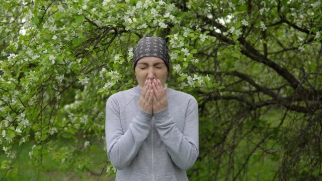 Young-woman-sneezes-near-an-apple-tree,-an-allergy