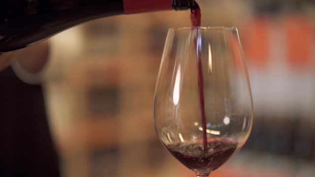 Slow-pouring-red-wine-into-a-wine-glass.-Female-hand-pours-wine-into-a-wine-glass-close-up.