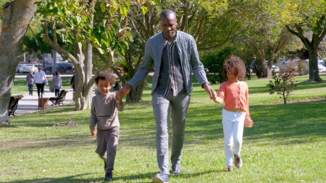 Happy-African-American-father-holding-hands-with-kids