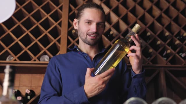 Smiling-Man-With-Bottle-Of-Wine-In-Cellar-At-Winery-Restaurant