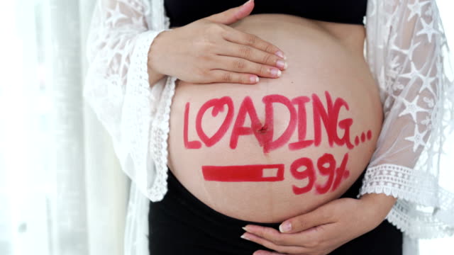 panning-shot-of-pregnant-woman-with-loading-99%-concept-painted-on-her-belly
