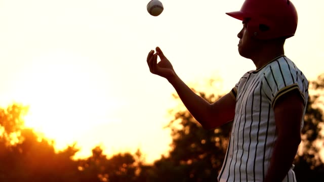 Baseball-Spieler-hält-einen-Baseball-mit-dem-Licht-des-Sonnenuntergangs