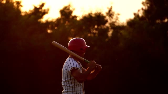 Baseballspieler-hält-einen-Baseballschläger-mit-dem-Licht-des-Sonnenuntergangs