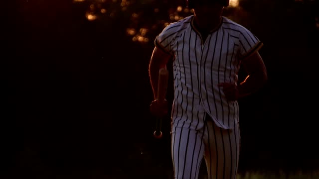 Baseballspieler-hält-einen-Baseballschläger-mit-dem-Licht-des-Sonnenuntergangs