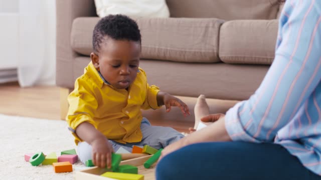Mutter-und-Baby-spielen-mit-Spielzeugblöcken-zu-Hause