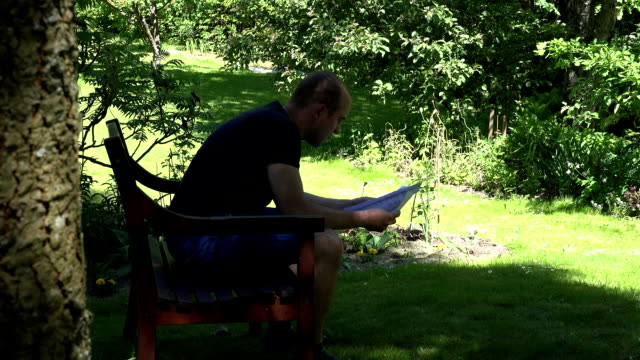man-sad-reaction-after-reading-letter-sitting-on-bench-in-park.-FullHD