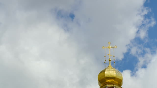 Die-goldene-Kuppel-der-eine-orthodoxe-Kirche-auf-dem-Hintergrund-des-blauen-Himmels-und-der-Wolken.-Goldenes-Kreuz-auf-der-Kuppel-des-Tempels.-Zeitraffer.-Ein-geloopten-Clip-ohne-Pausen.-4K-Ultra-HD,-UHD