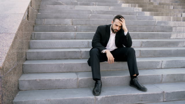 Un-joven-empresario-molesto-con-estrés-y-sentado-en-las-escaleras-de-la-calle.-Empresario-que-tiene-el-concepto-de-problemas-de-trato