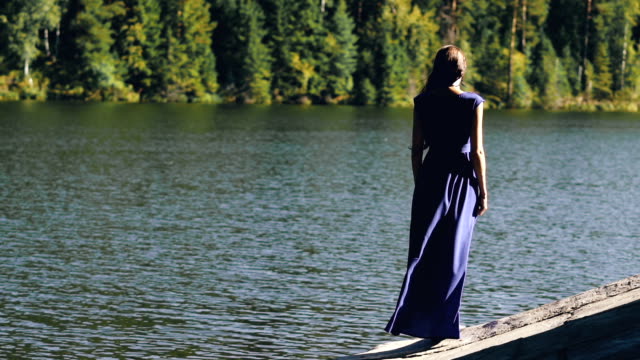 Slowmotion-der-schönen-jungen-Frau-im-langen-Kleid-stehen-am-Ufer-in-der-Nähe-von-See
