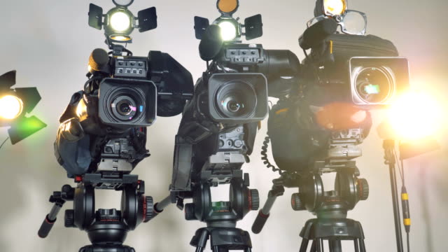 A-low-close-view-on-three-video-cameras-on-massive-stands.