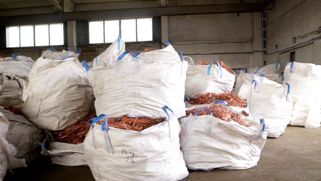 huge-white-bags-with-copper-scrap-from-wires-are-lying-in-a-warehouse-of-scrap-metal-processing-plant
