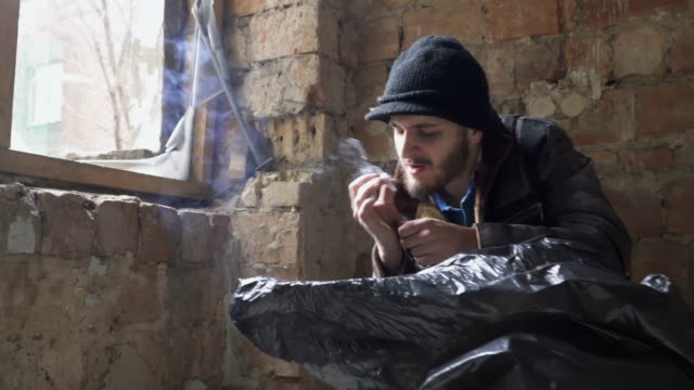 Young-bearded-homeless-smoking-cigarette