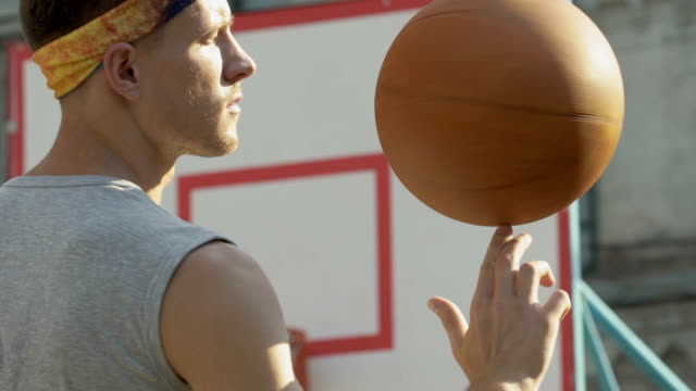 Chico-guapo-spinning-baloncesto-en-su-dedo,-mostrando-profesionalismo,-deporte