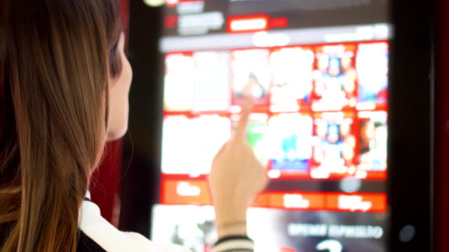 Teenager-buying-movie-ticket-from-vending-machine-at-cinema.-Female-make-gestures-by-touching-screen
