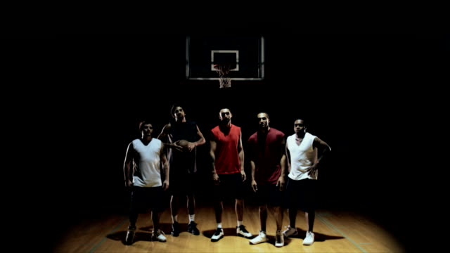 Grupo-de-jugadores-de-baloncesto,-posando-en-la-cancha,-lanzar-bola-y-dejando.