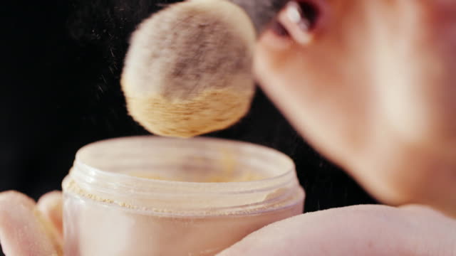 Female-hands-make-up-artist-dipping-brush-in-crushed-powder-for-face-close-up