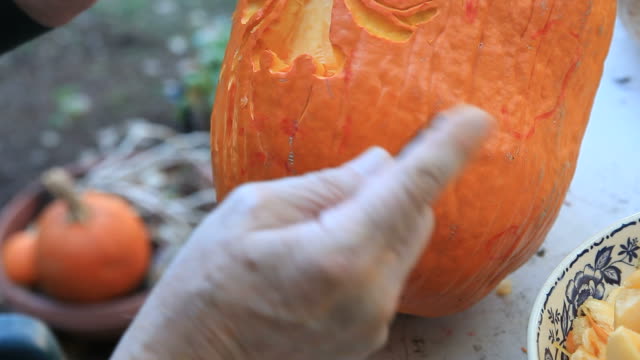 Closeup-man-carves-Halloween-pumpkin