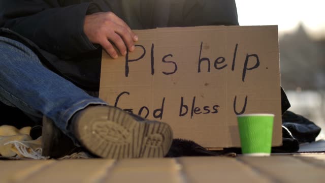 Close-up-beggar-male's-legs-and-cardboard-sign