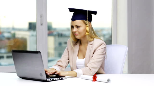 Studierende-in-Bachelor-Cap-mit-Laptop-und-Diplom