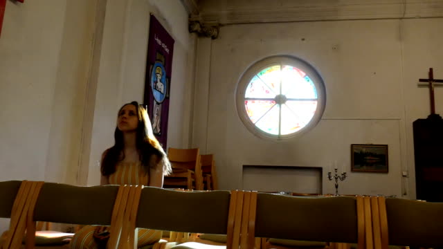 Young-caucasian-religious-devoted-woman-on-the-bench-in-Catholic-Church