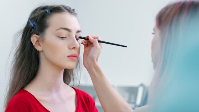 Close-up-model-face-during-working-of-professional-female-make-up-artist-applying-eyeshadow