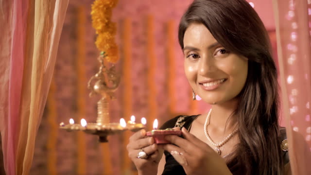 A-close-up-of-beautiful-and-traditional-woman-lighting-a-lamp-during-Diwali-festival.