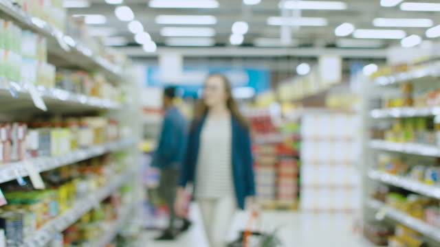 Unscharfe-Aufnahmen-im-Supermarkt-groß-und-hell.-Menschen-und-Kunden-zu-Fuß-durch-die-Gänge-verschiedene-nützliche-Gegenstände-kaufen.