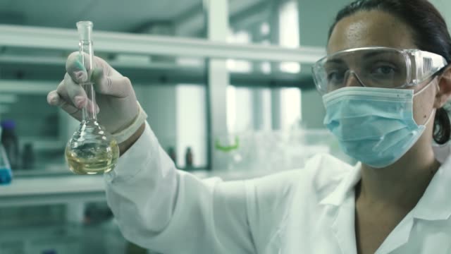 Técnico-de-laboratorio-hermosas-tiras-el-frasco-con-un-líquido-químico